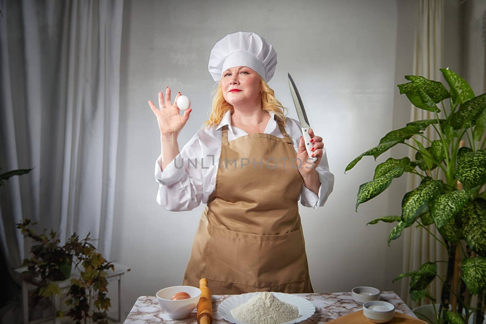 A fat funny female cook in a hat and apron poses in the kitchen and takes selfie. Good cooking and body positive