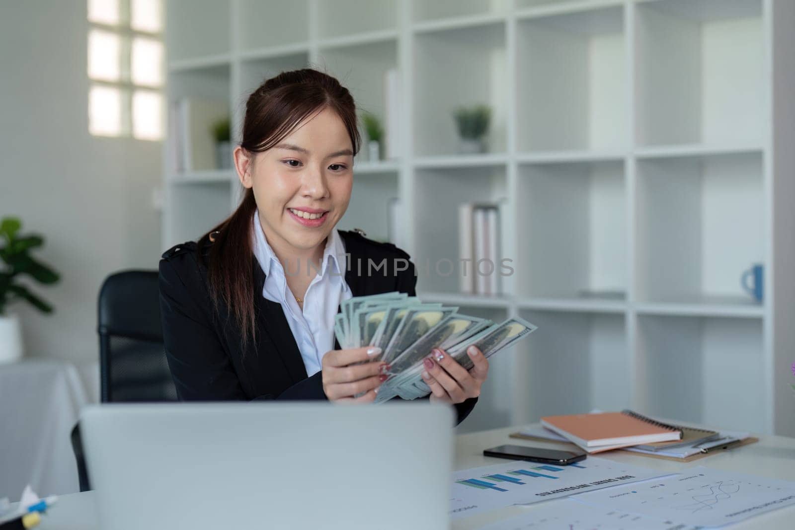 Businesswoman or financial bookkeeper holding bundle of money dollar for payment salary and income. entrepreneur counting money cash count salary profit finance at office.