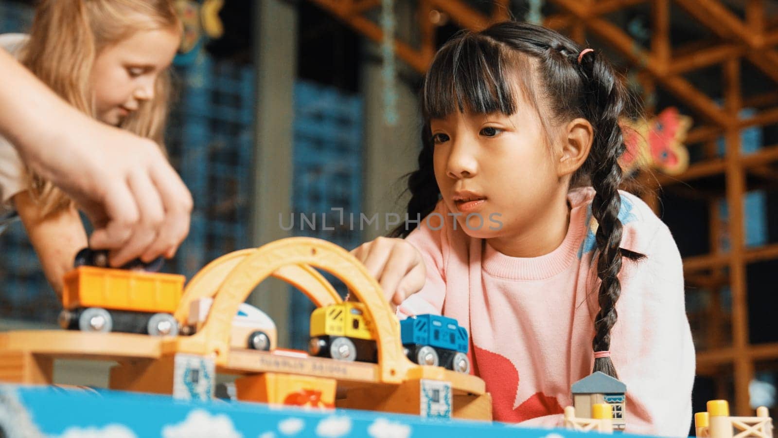 Closeup of cute asian girl play car toy with friend at play room. Diverse children using car model to improve imagination. Adorable children enjoy playing robotic model. Educational game. Erudition.