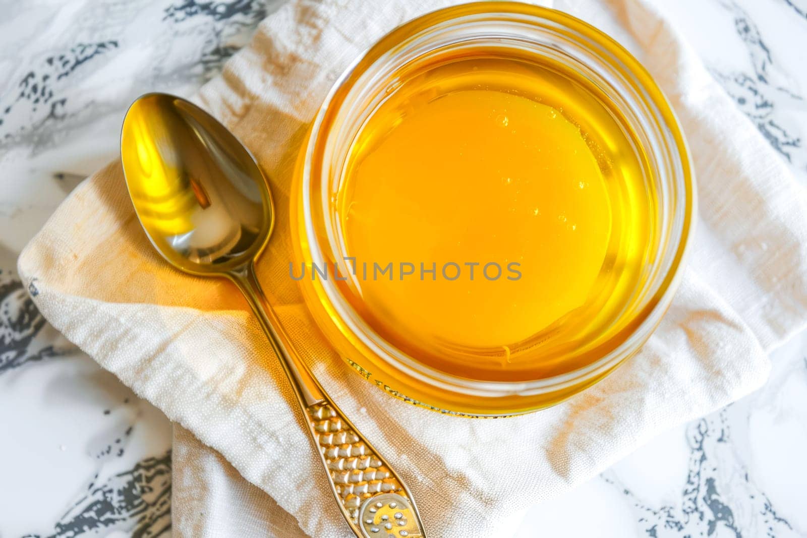 Top view, jar of ghee on a linen napkin with a spoon. by OlgaGubskaya