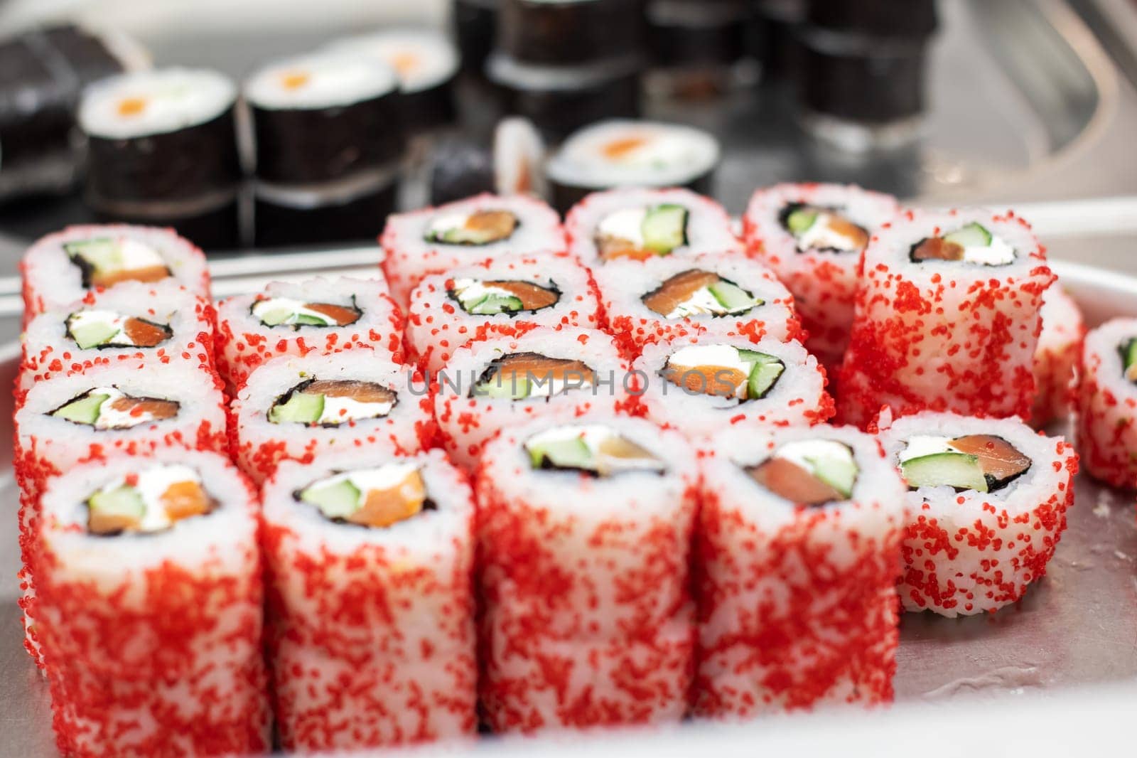 A variety of sushi rolls with red sprinkles on top, a popular ingredient in Japanese and Korean cuisine like California roll or Gimbap