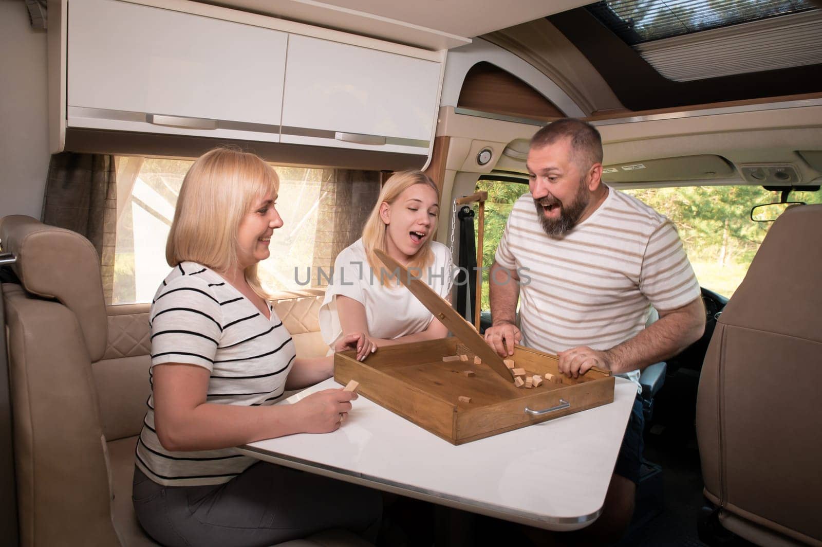 A family of three is playing a board game while sitting in a motorhome.