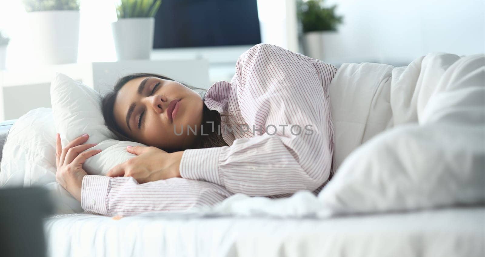 Beautiful indian woman peacefully lying in bed sleeping early morning while alarm clock going to ring awakening. Early wake up, not getting enough sleep, oversleep, getting work time concept