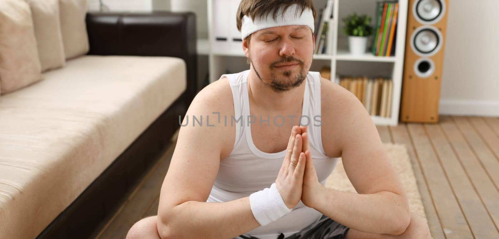 A young man practicing yoga and Pilates at home dreams of an excellent figure being restored after an intense load for the body to lose weight.