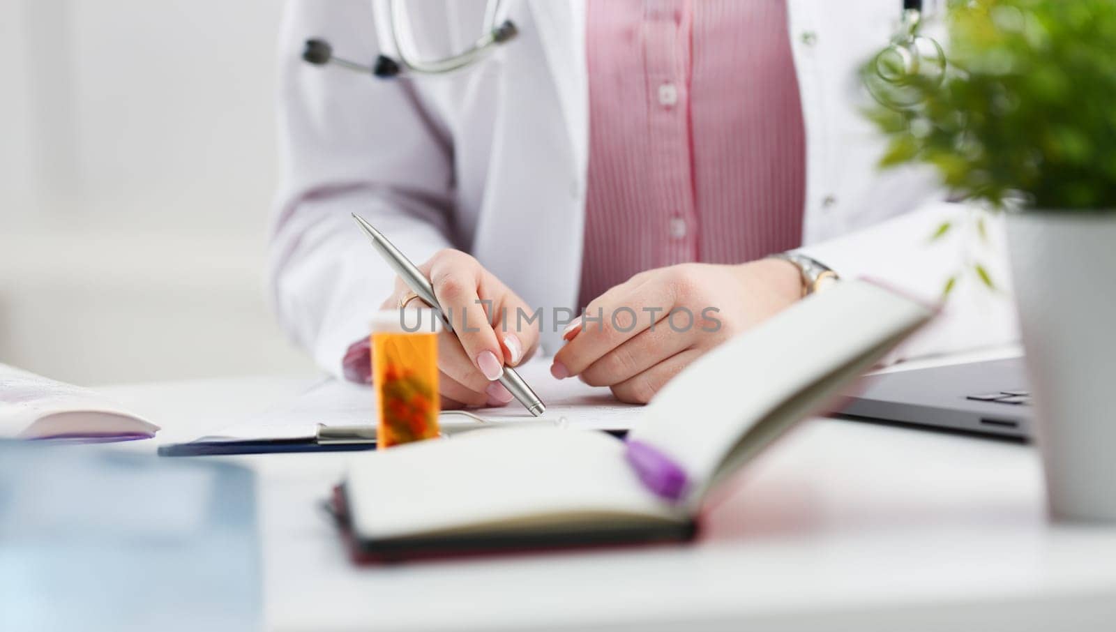 Female medicine doctor hand hold jar of pills and write prescription to patient at worktable. Panacea and life save, prescribing treatment, legal drug store concept. Empty form ready to be used