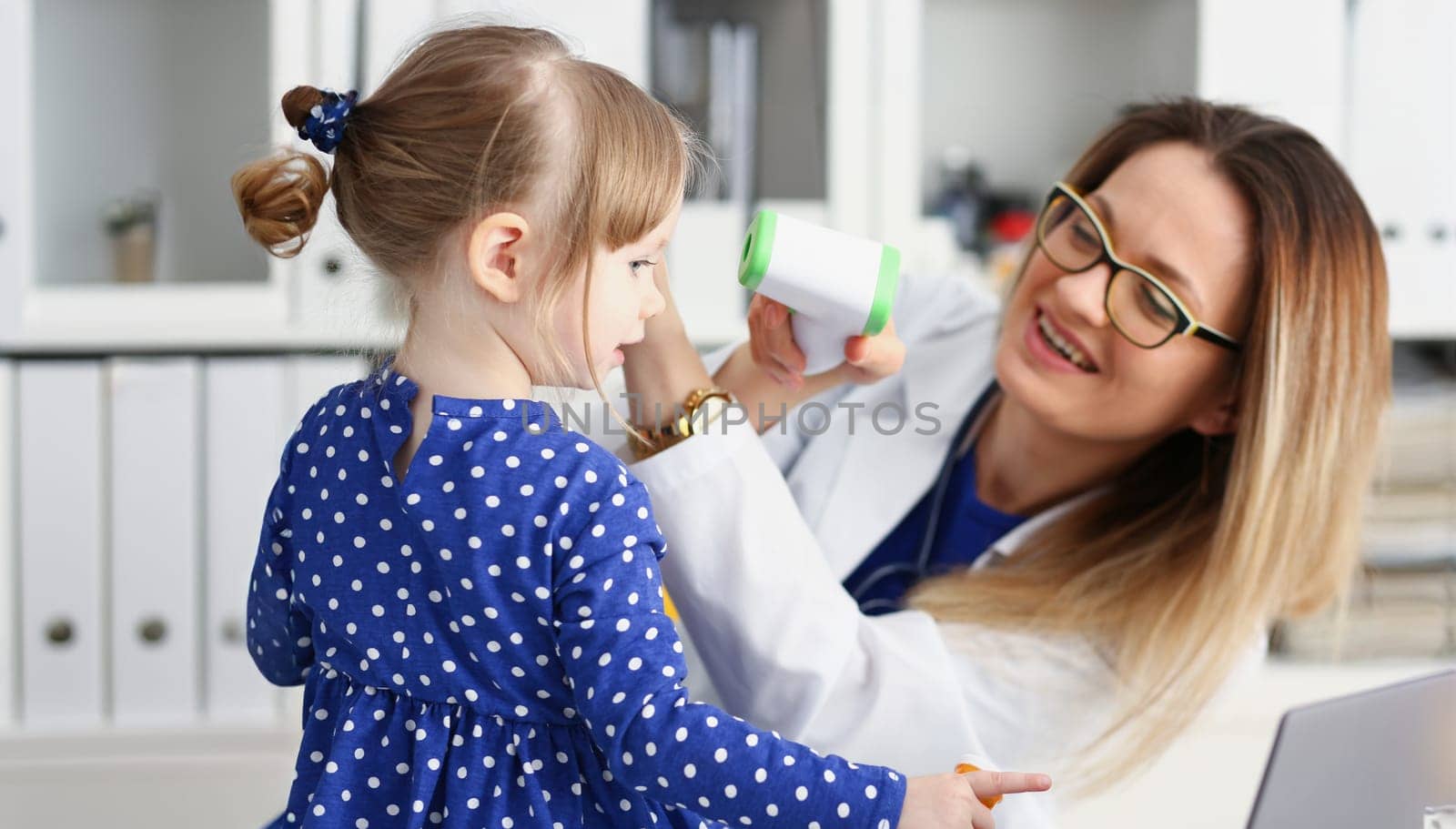 At doctor reception little child. The pediatrician measures temperature with an infrared laser thermometer rise high very quickly