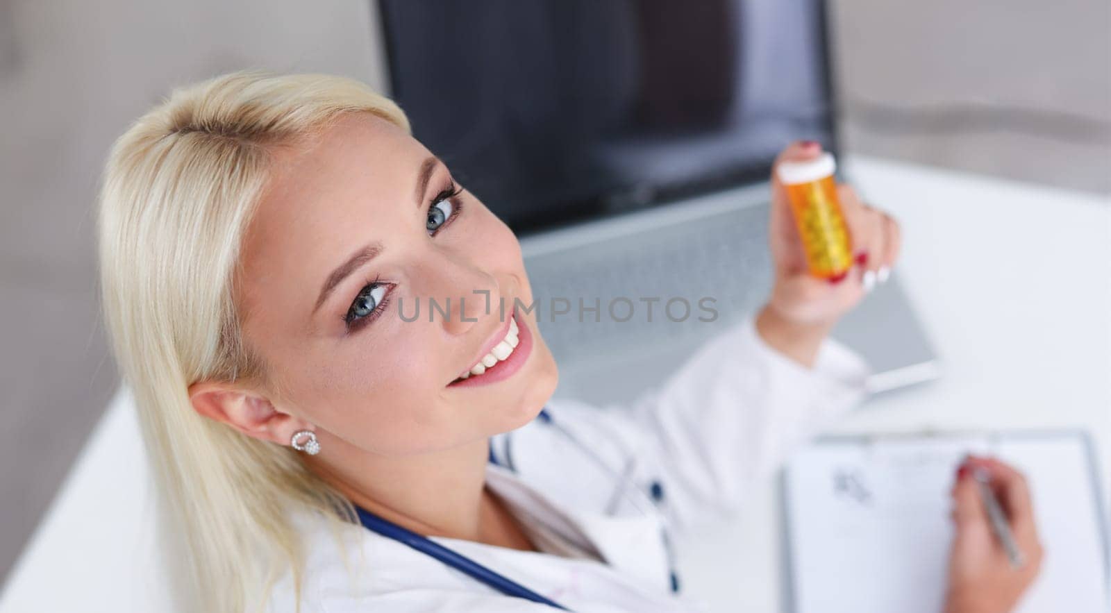 Beautiful smiling female doctor write prescription by kuprevich