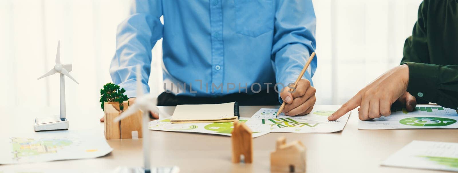 Business people invest in green business plan at meeting room on table with house model and wind mill placed represented eco house and renewable energy. Closeup. Delineation.