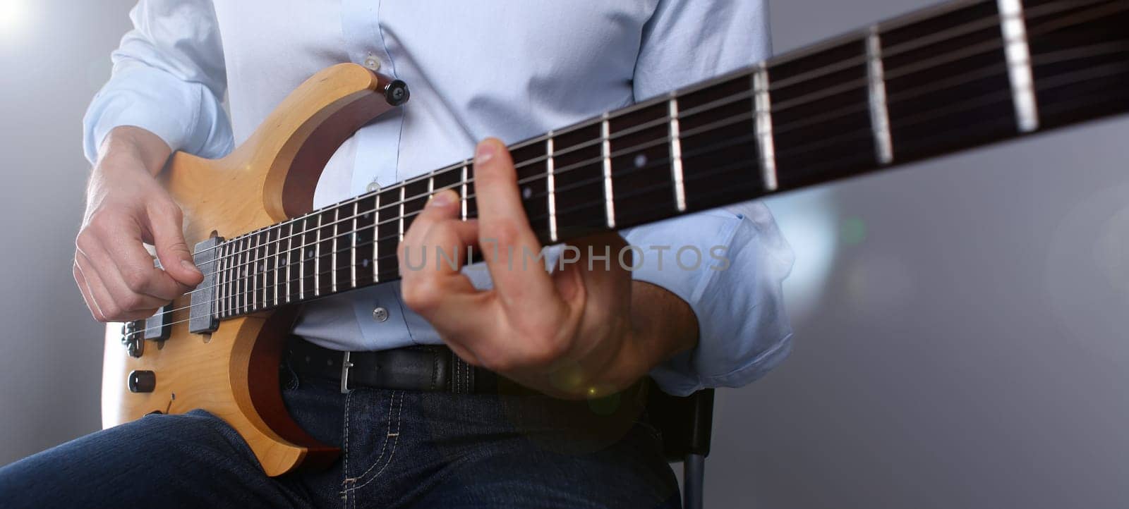 Male arms holding and playing classic shape wooden electric guitar closeup. Six stringed learning musical school education art leisure electrical vintage stage shop having fun enjoying hobby concept