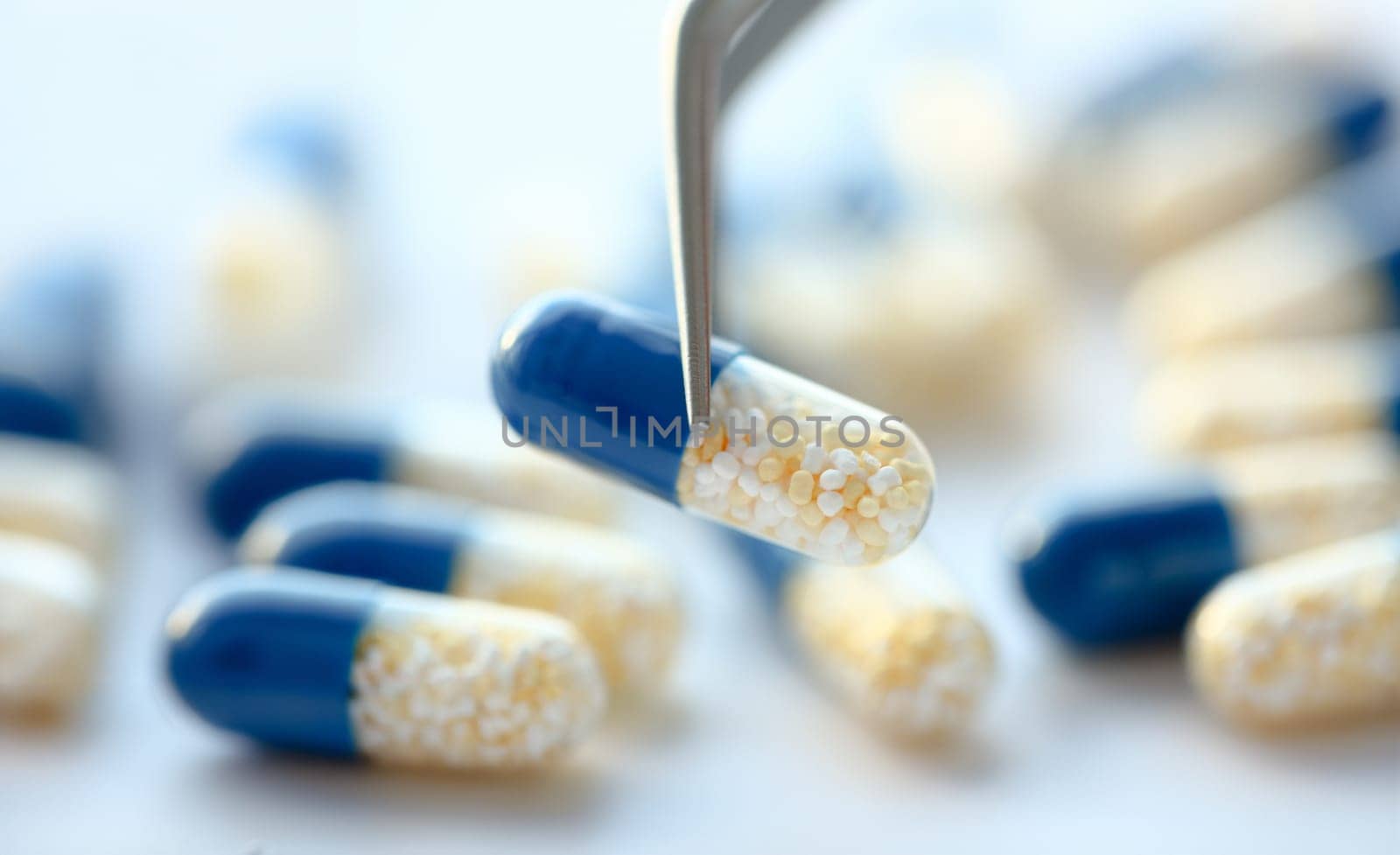 Arm lifting up pill with tweezers closeup by kuprevich