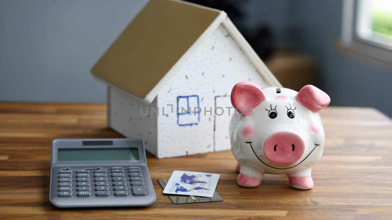 Calculator with piggy bank against home background closeup. Mortage credit concept