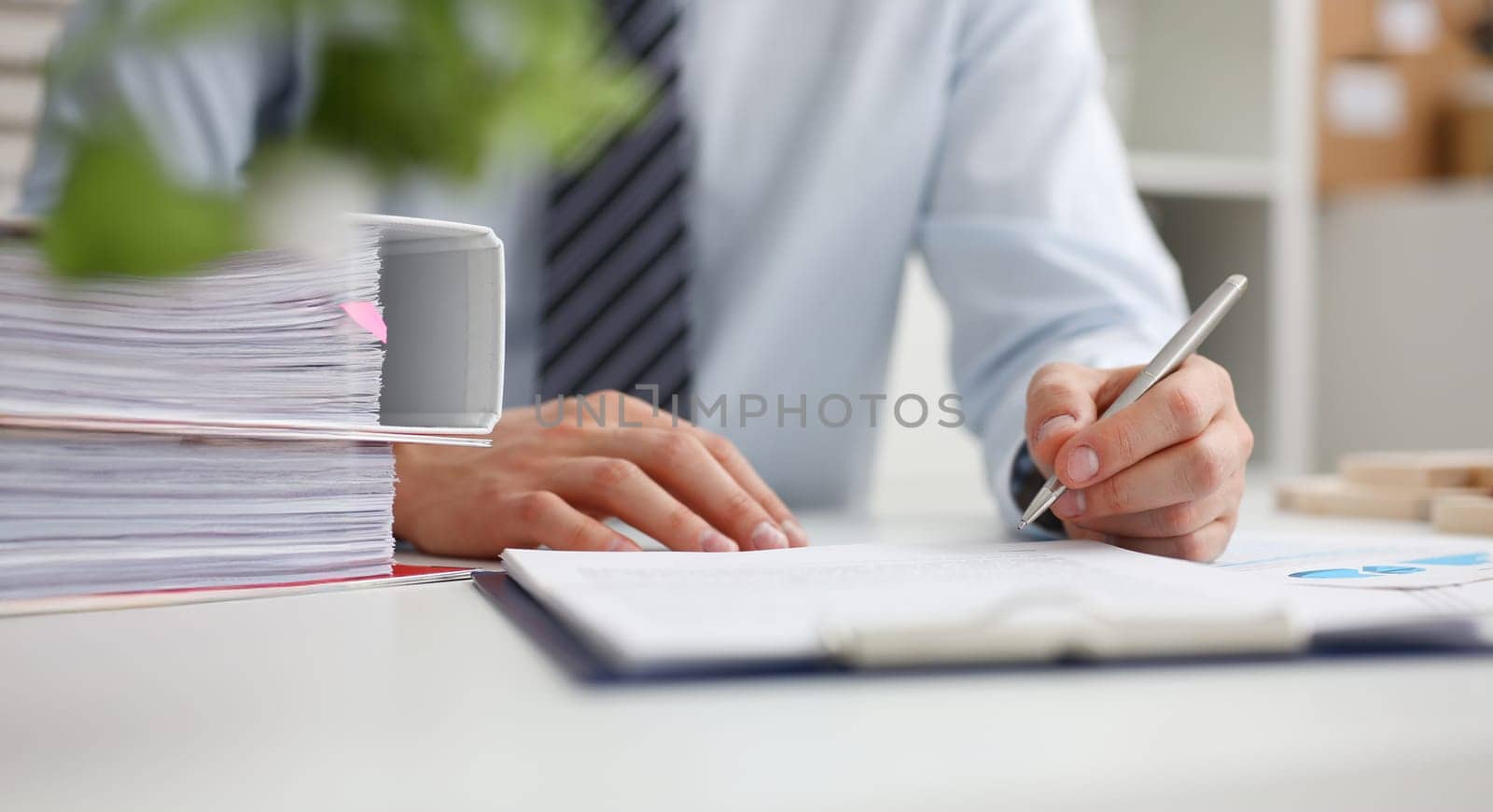 Male hand holding silver pen ready to make note in opened notebook sheet. Businessman in suit at workspace make thoughts records at personal organizer white collar conference signature concept