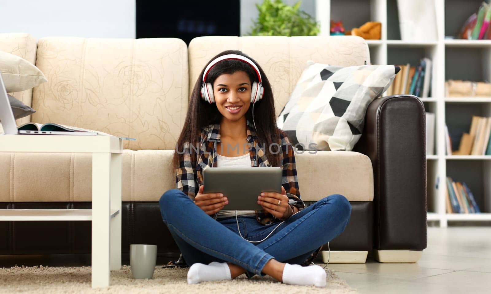 Black ordinary female american teen portrait at home sofa remote education concept. Girl hold tablet in hand music apps teacher checks homework online university library learning foreign languages