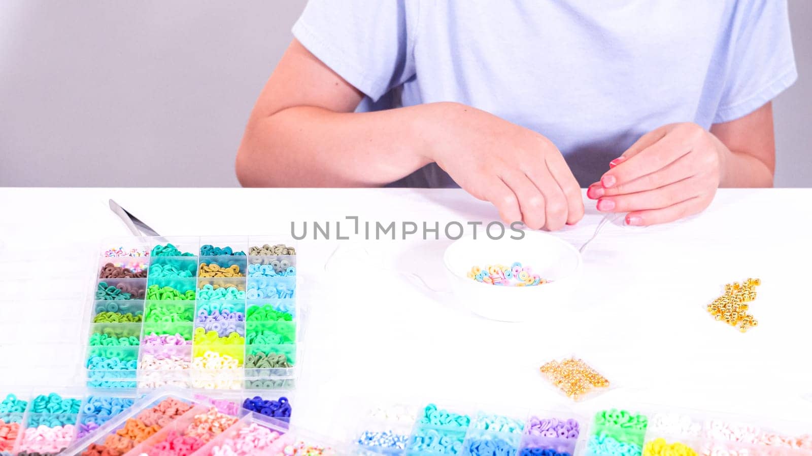 Delicate fingers of a young girl navigate through a treasure trove of bright, multicolored beads, each compartment revealing a new hue to choose from.