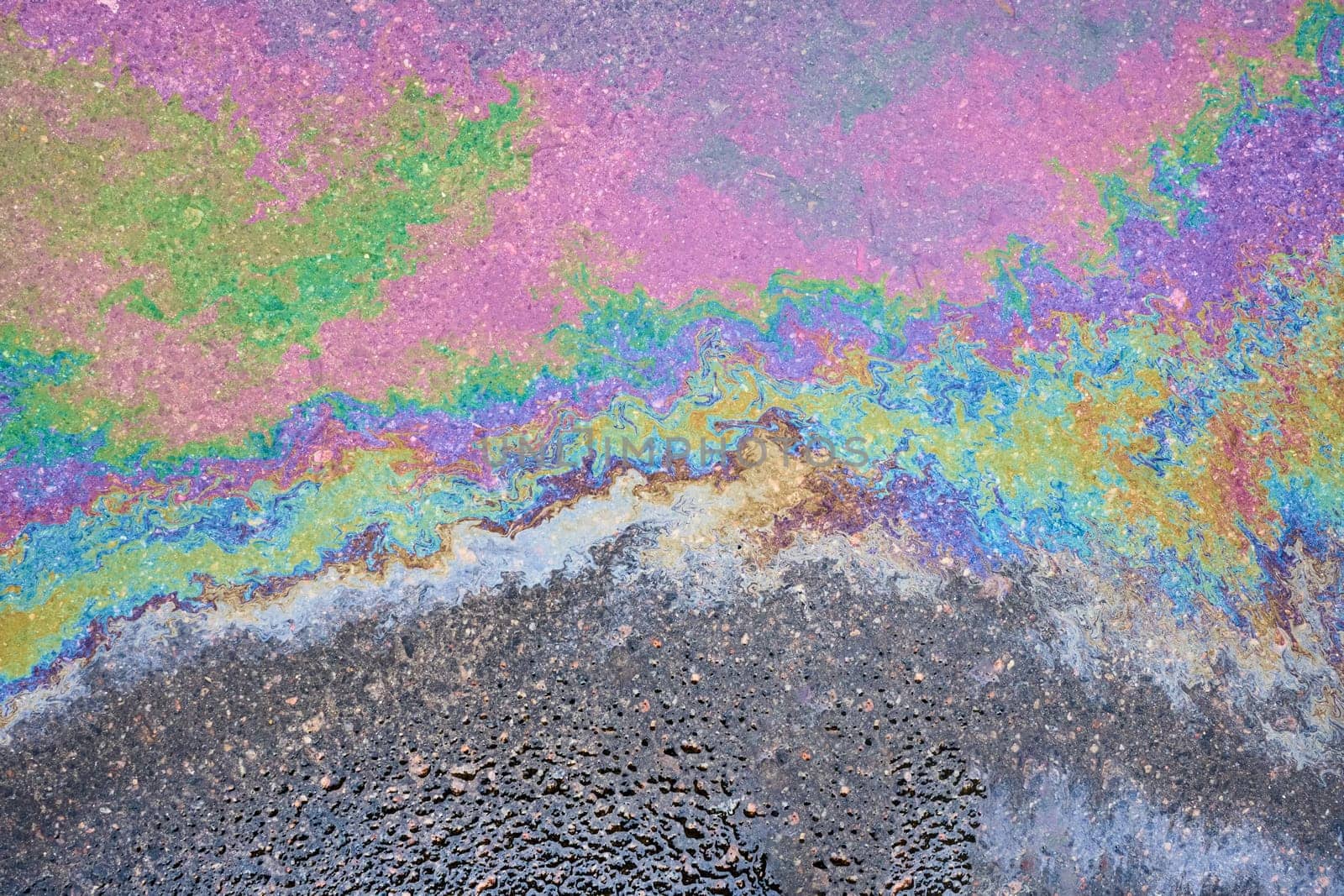 Captivating close-up of the opalescent sheen of a petrochemical spill on saturated asphalt. by AliaksandrFilimonau