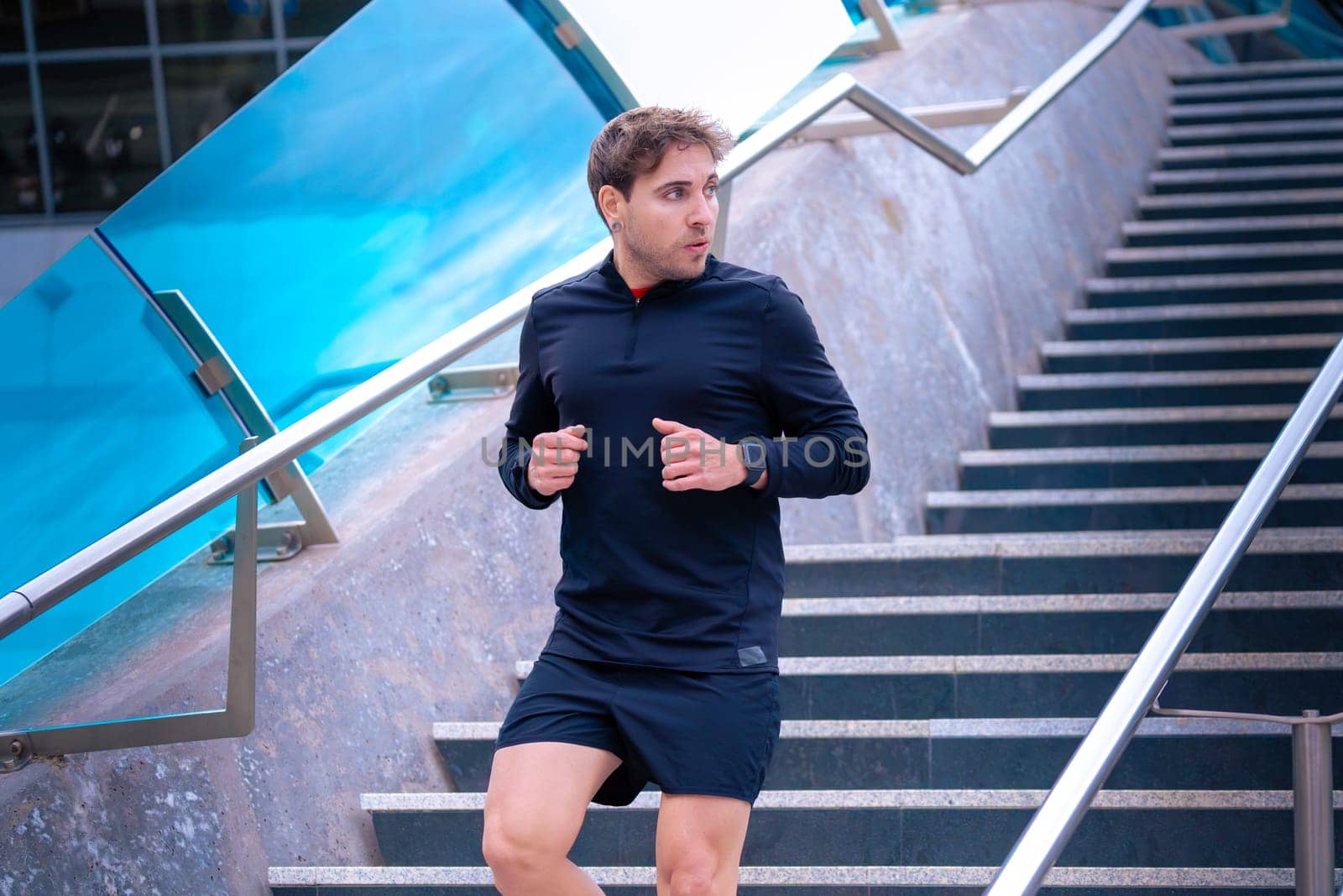 Man running down stairs,with bottle of water in hand doing his daily cardio and warm up exercise. Physical activity concept