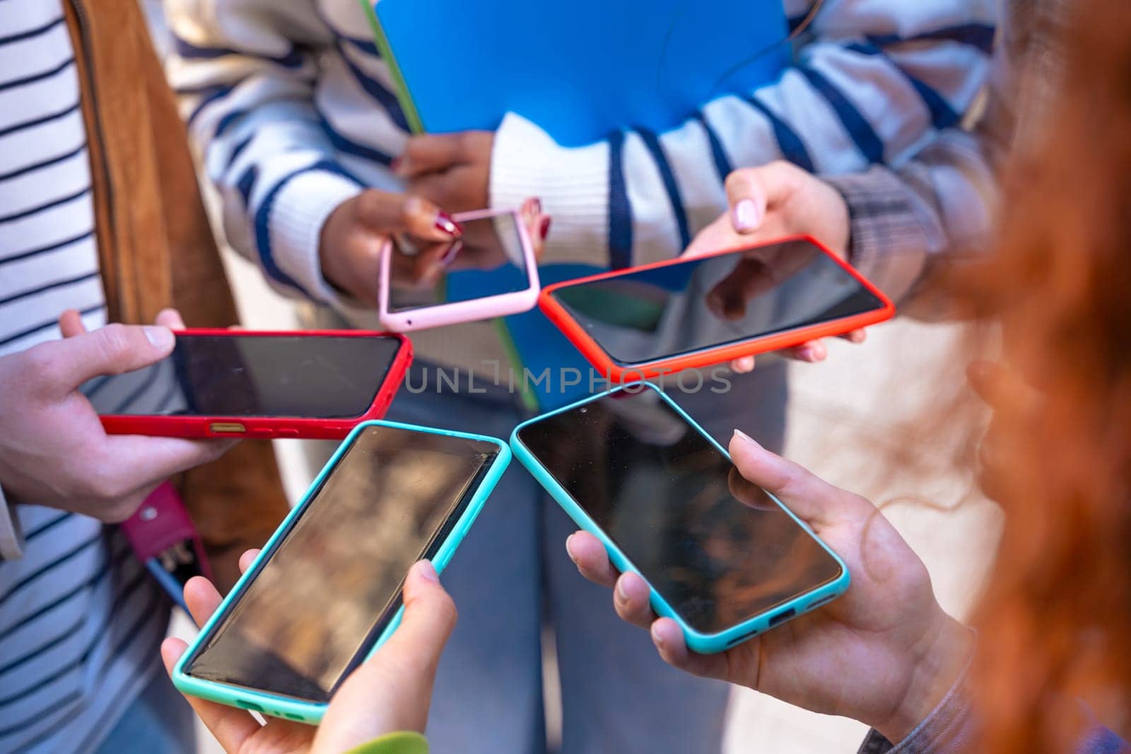 Group of friends using looking at their smartphones Multiracial teenagers browsing the internet with mobile phone on campus