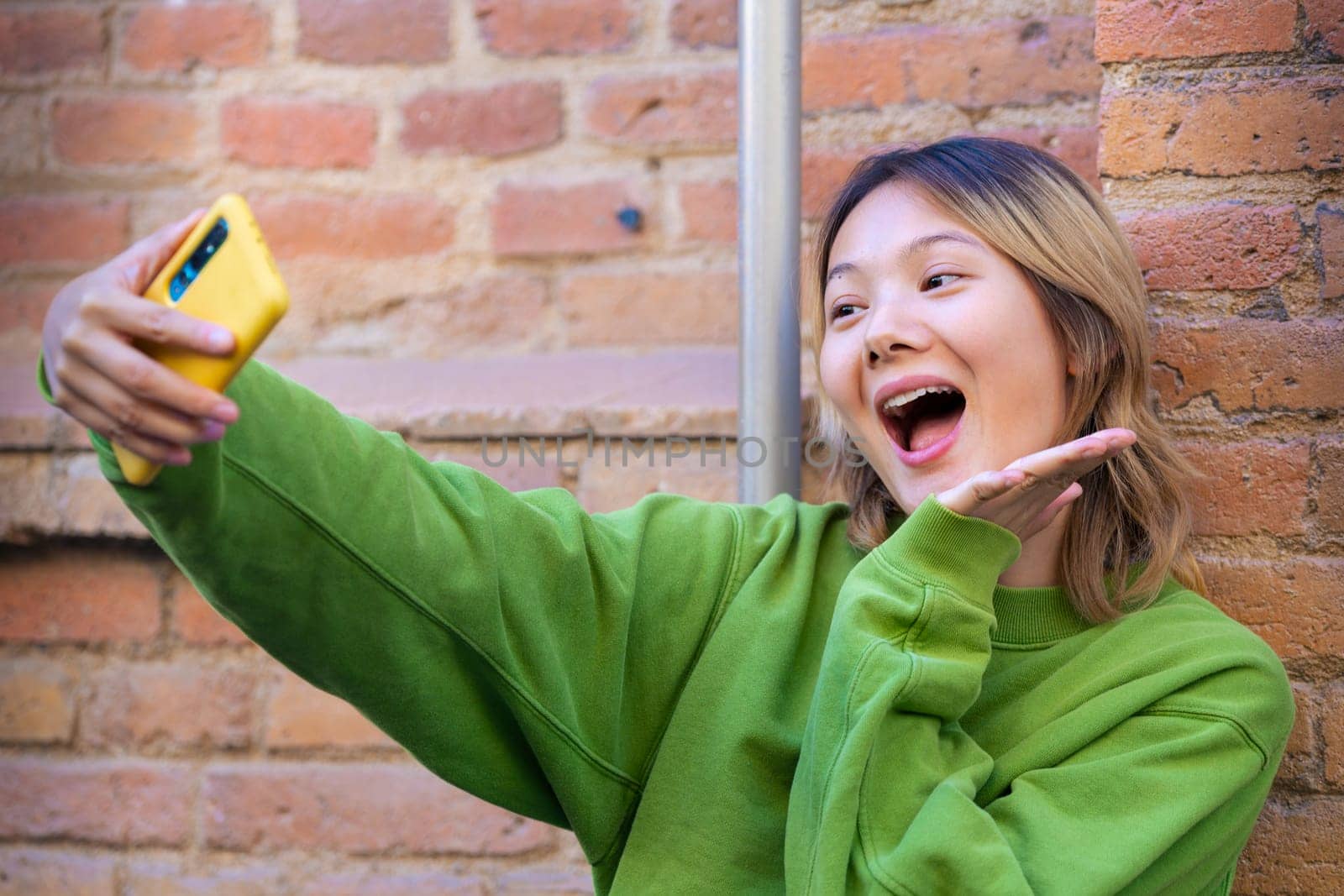 Happy young chinese taking a selfie with smartphone.