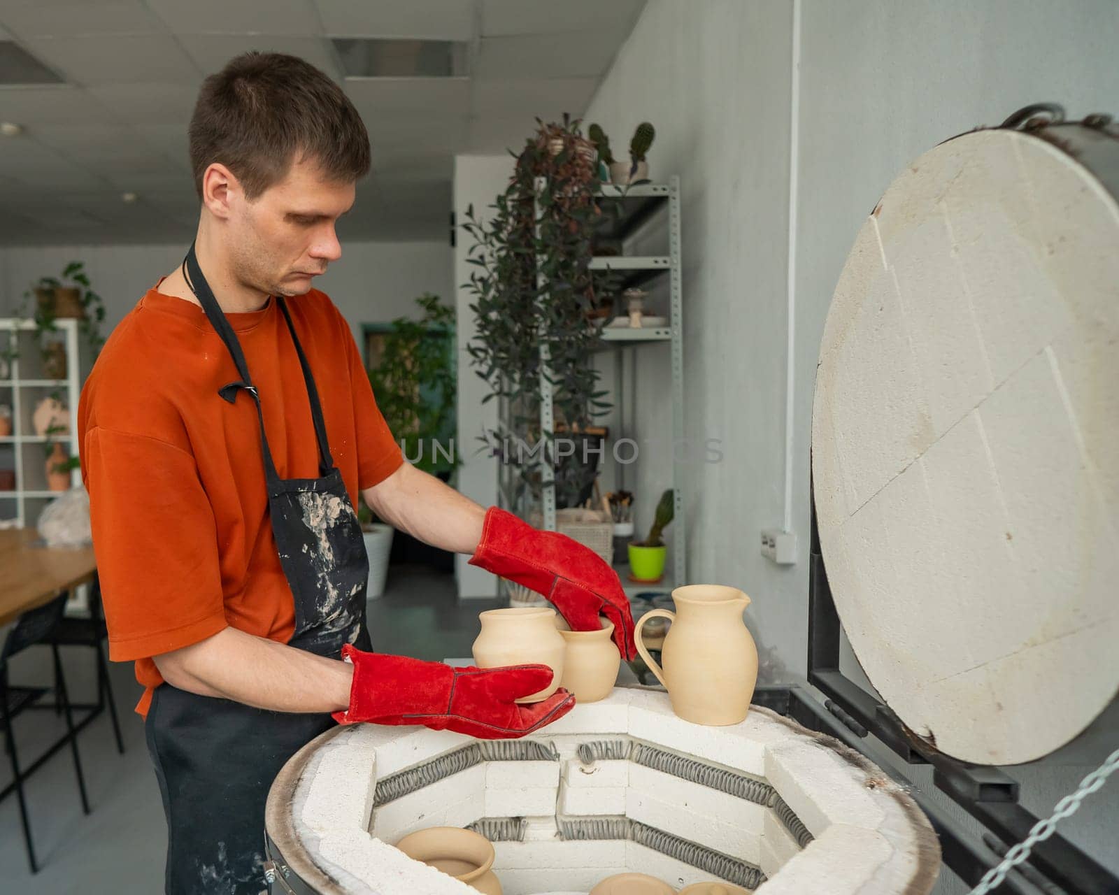 Caucasian man loading ceramic products into a special kiln