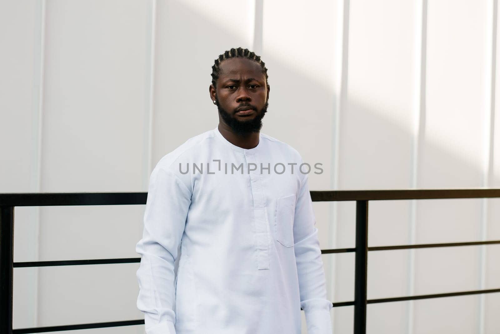 Close up portrait of a happy african american man smiling wearing ethnic dashiki clothes outdoor in summer street white wall. Millennial generation student and youth. Copy space by Satura86
