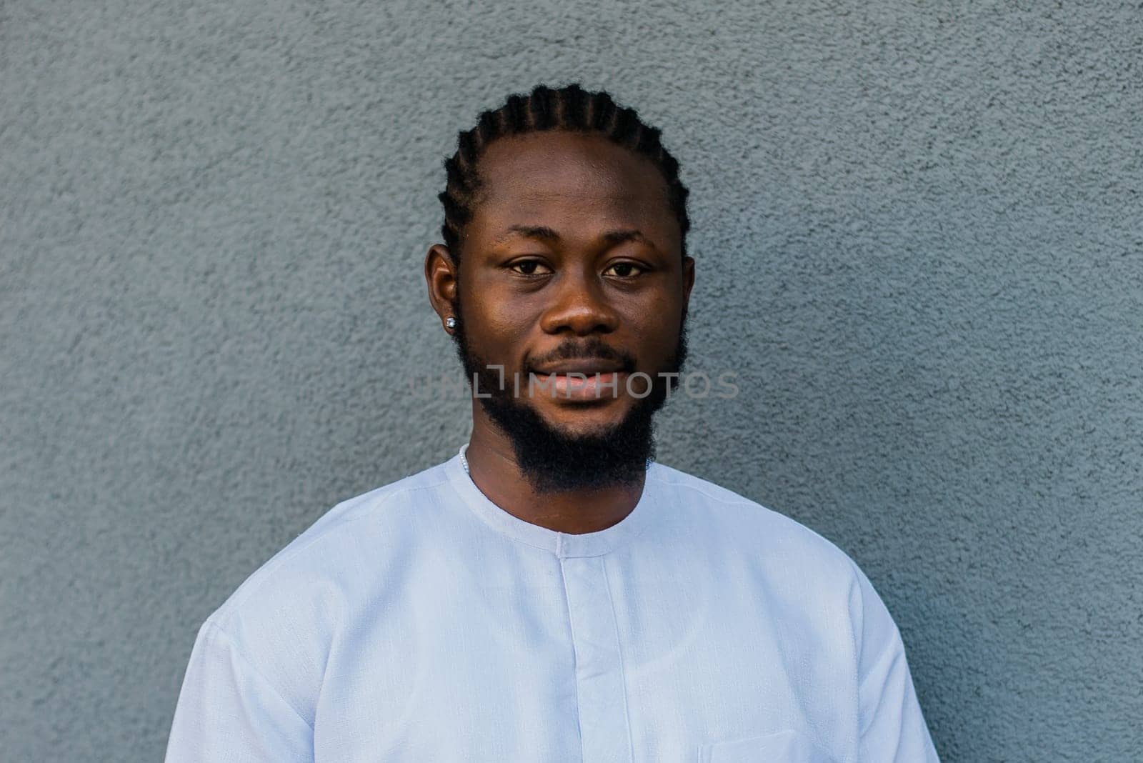 Close up portrait of a happy african american man smiling wearing ethnic dashiki clothes outdoor in summer street wall. Millennial generation student and youth. Copy space.