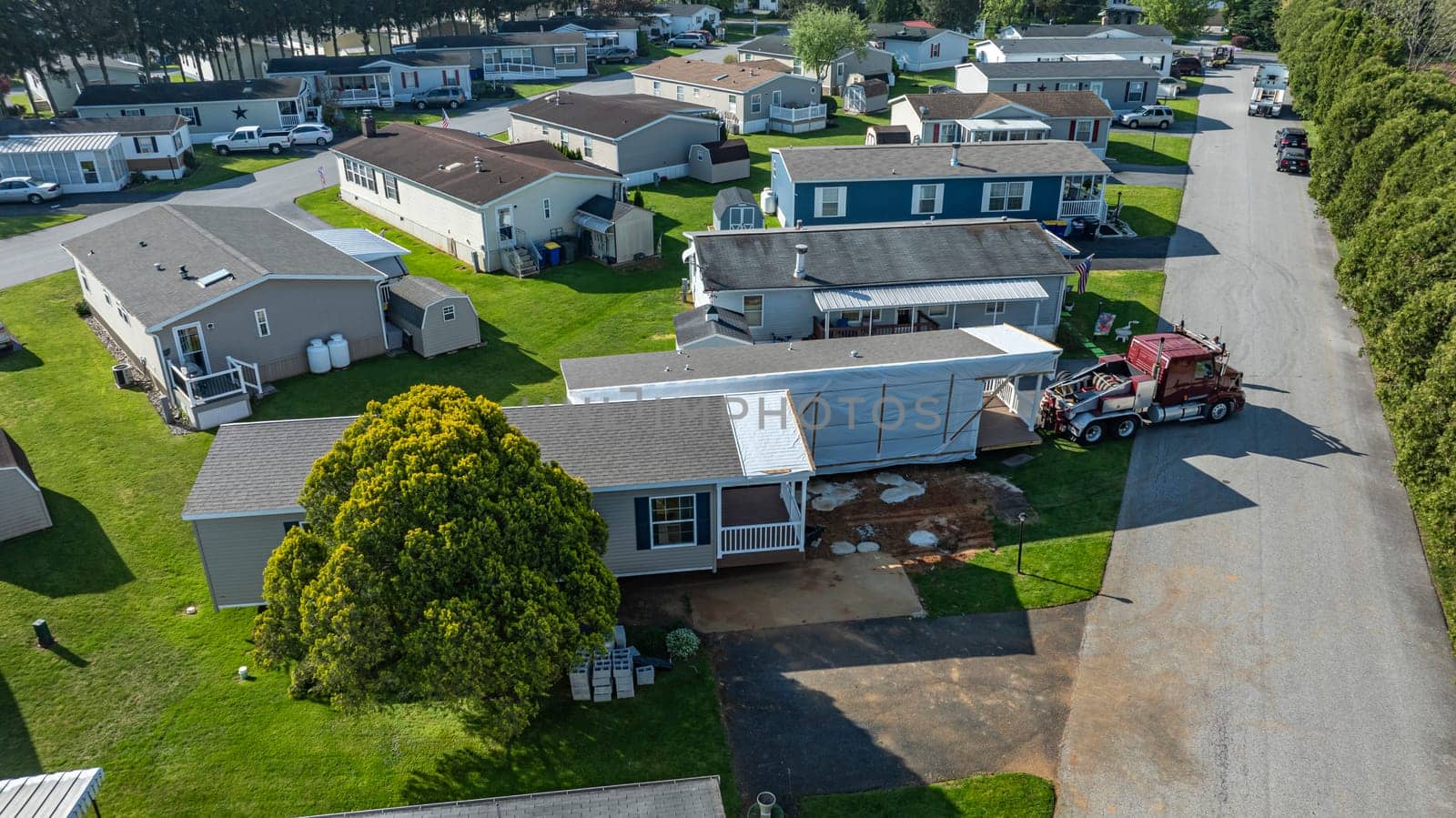 Aerial View of a Manufactured, Mobile, Prefab Double Wide Home Being Installed in a Lot in a Park by actionphoto50