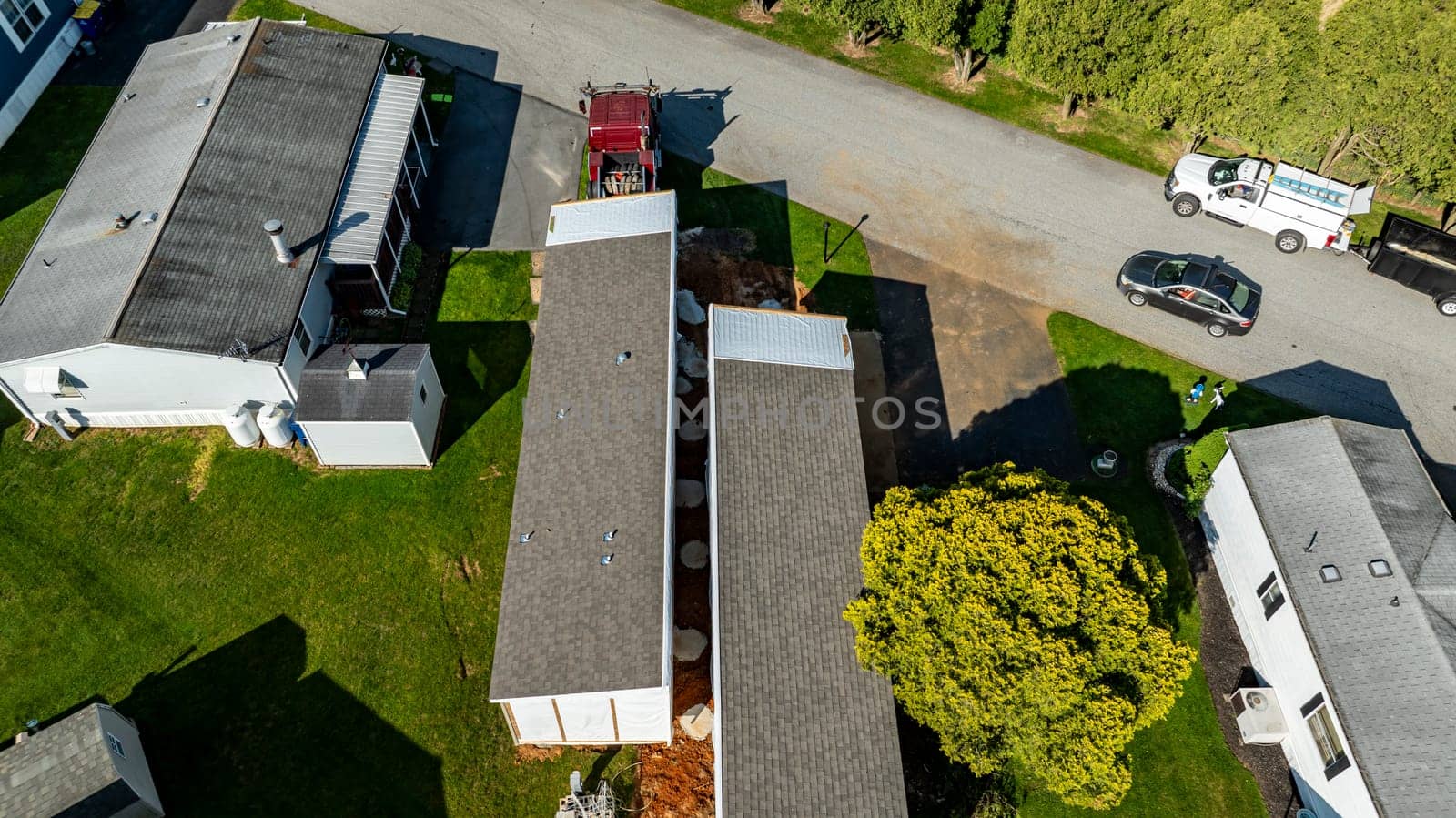 Aerial View of a Manufactured, Mobile, Prefab Double Wide Home Being Installed in a Lot in a Park by actionphoto50