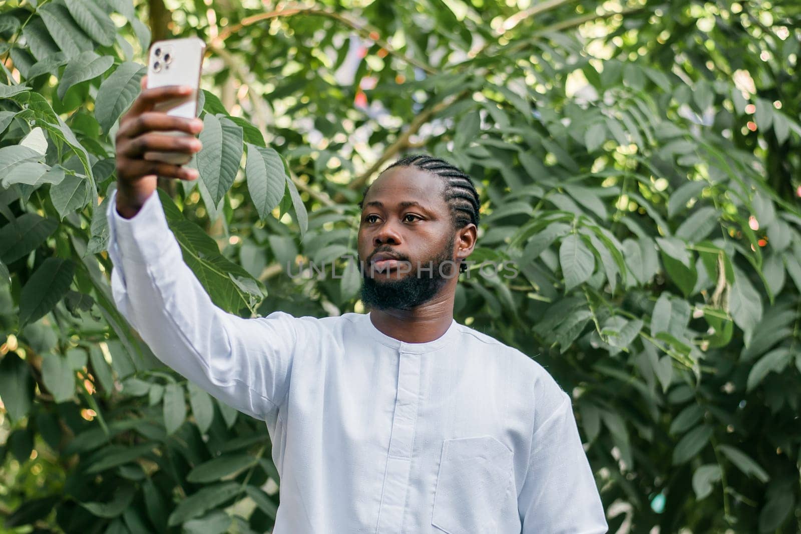 Happy young African American man in dashiki ethnic clothes taking selfie on brick wall background. Millennial generation student and youth