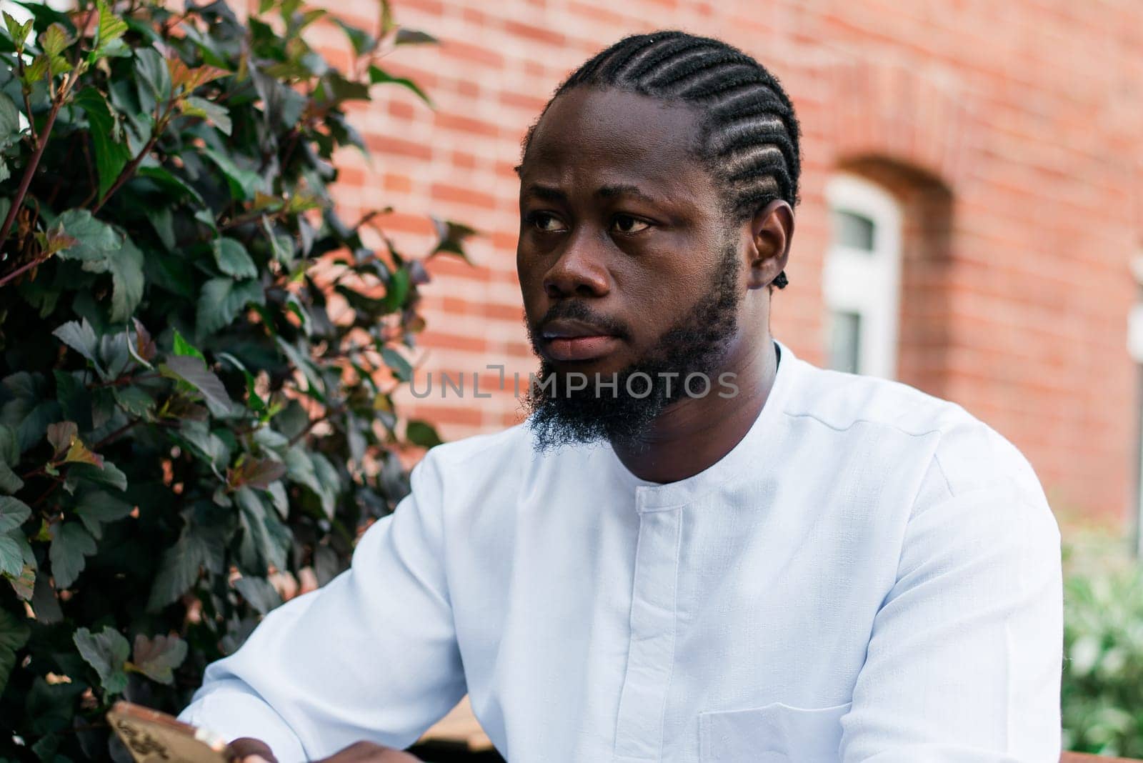 Cheerful male tourist portrait dress in white wear dashiki ethnic smiling at city street or small town background. African American travel model have free time. Millennial generation and gen z people.