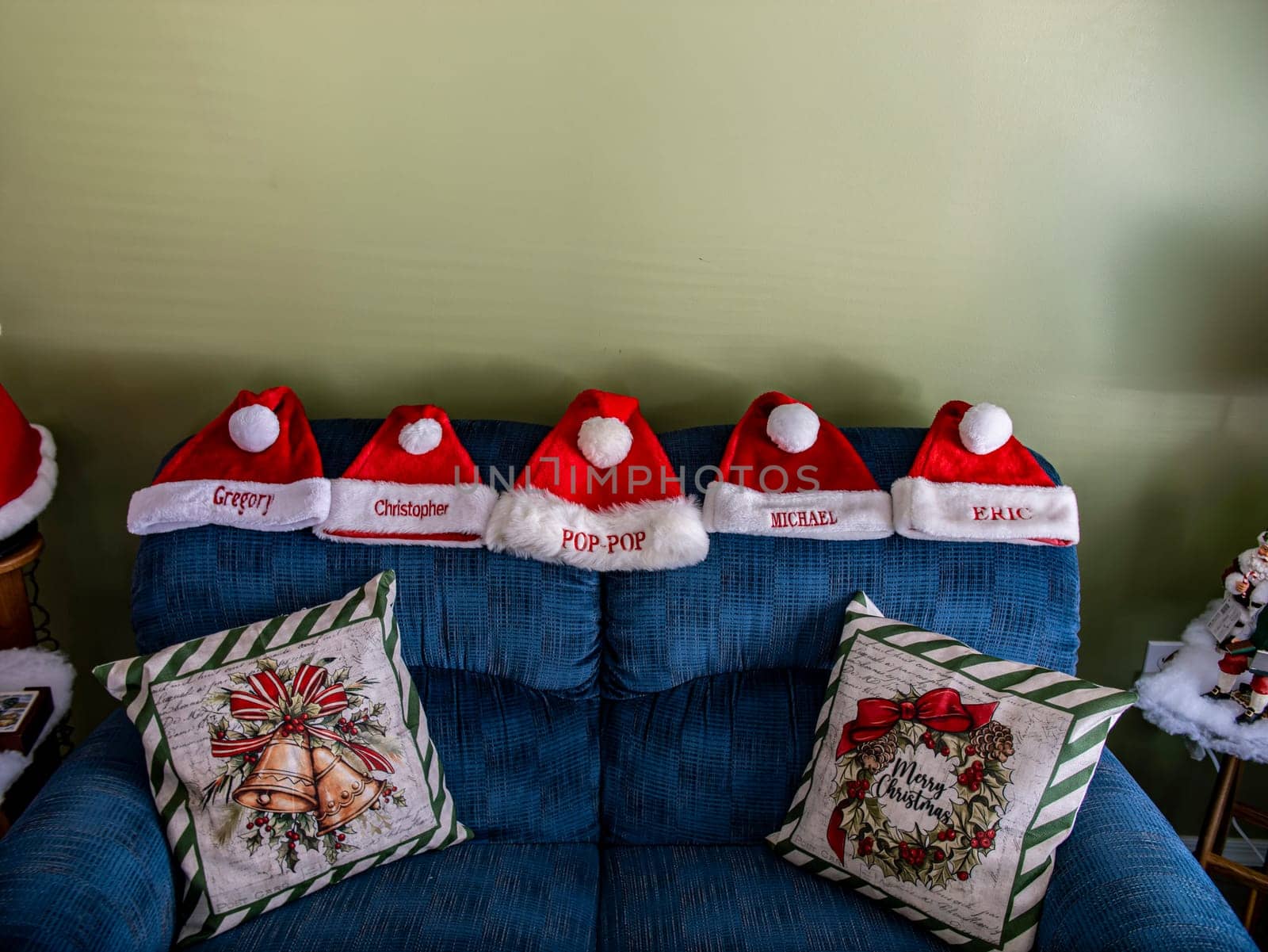 A group of five red santa hats are sitting on a blue couch by actionphoto50