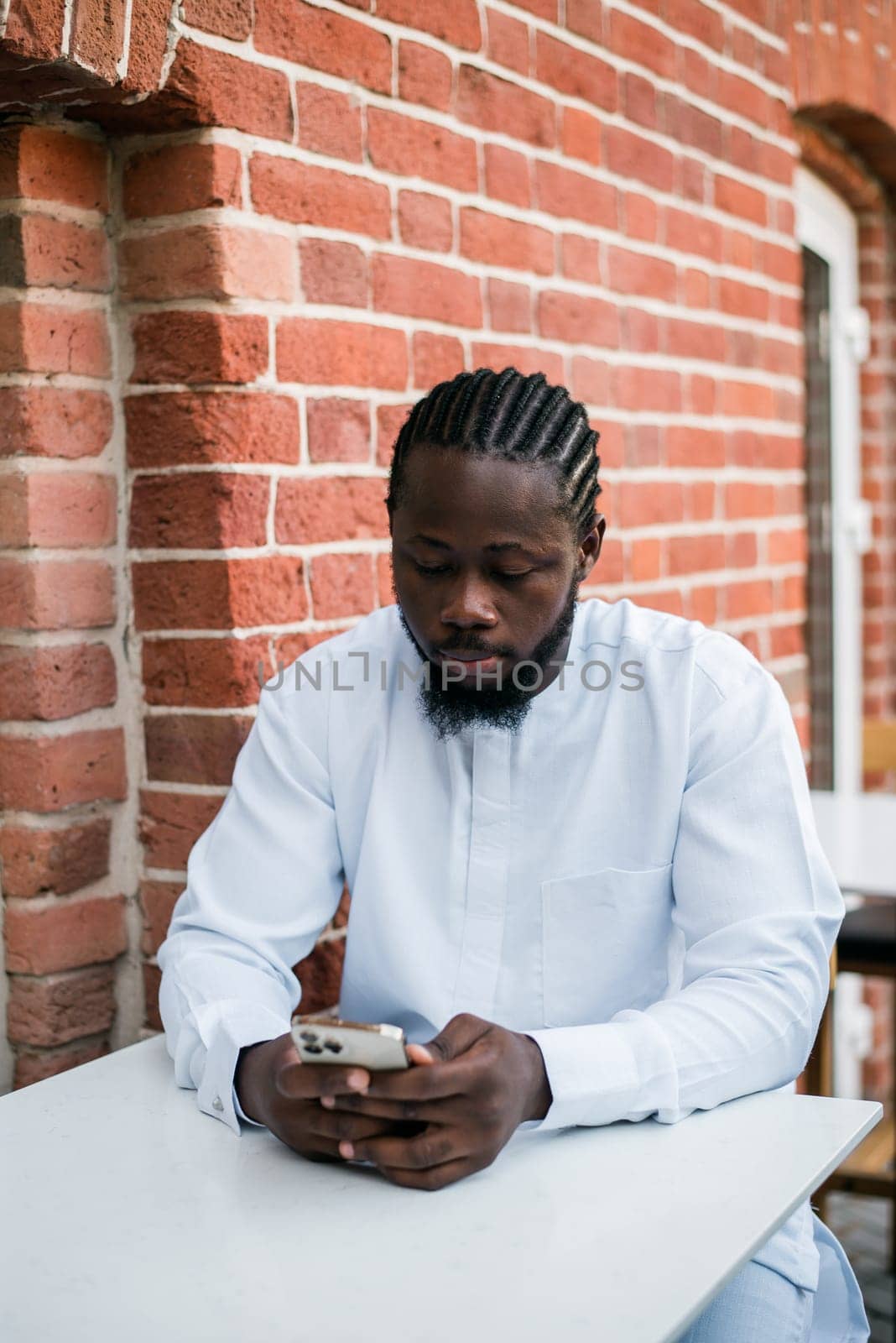 African american man checks cell phone in the street cafe in summer day. Millennial generation and gen z people. Social networks and dating app