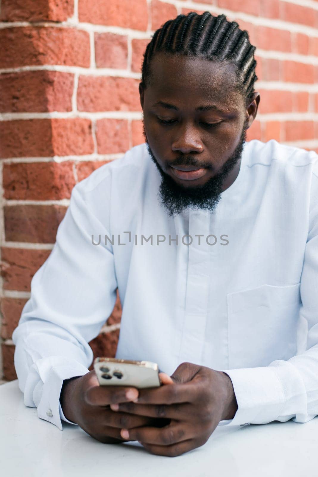 African american man checks cell phone in the street cafe in summer day. Millennial generation and gen z people. Social networks and dating app concept by Satura86