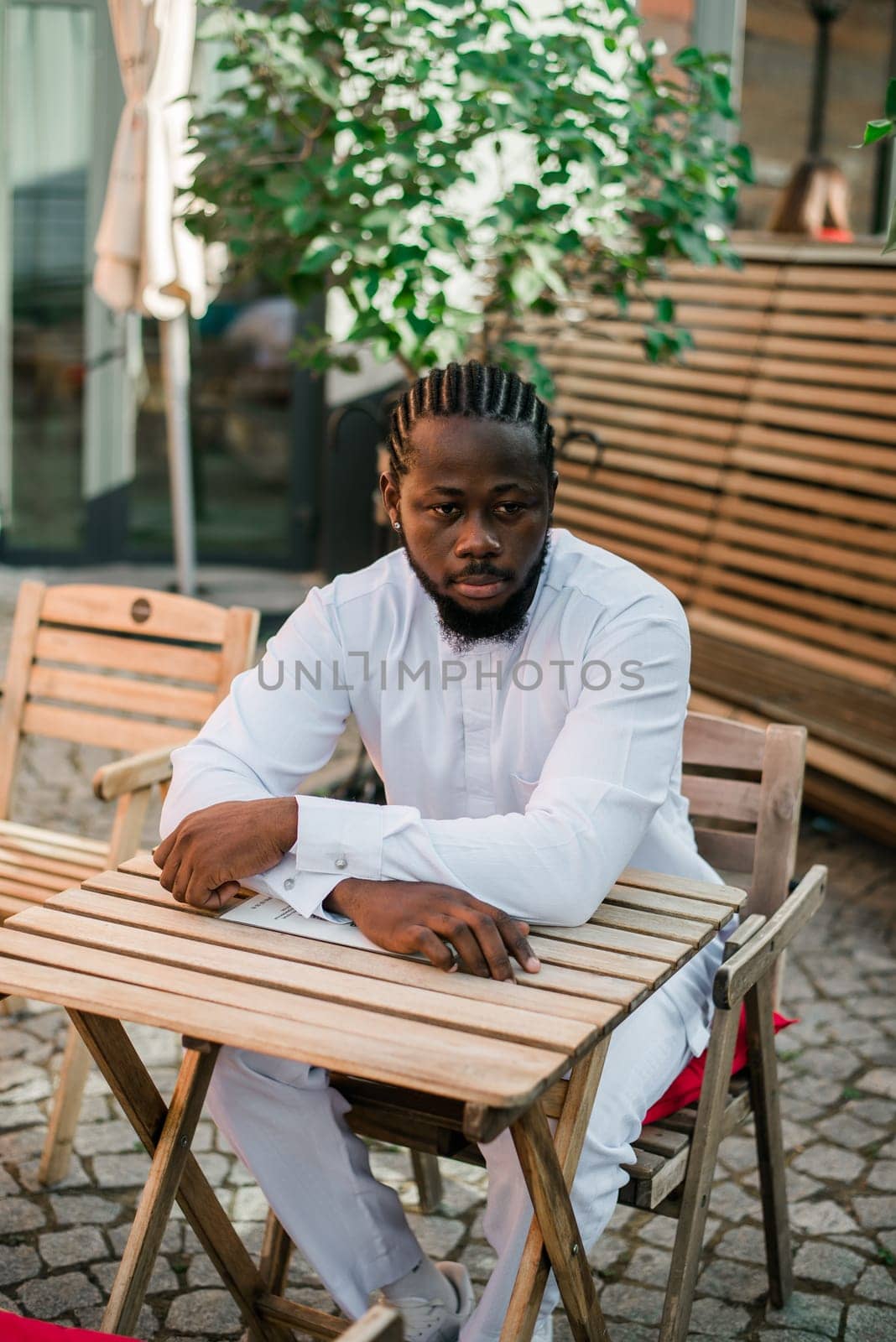 Cheerful male tourist portrait dress in white wear dashiki ethnic smiling at city street or small town background. African American travel model have free time. Millennial generation and gen z people.
