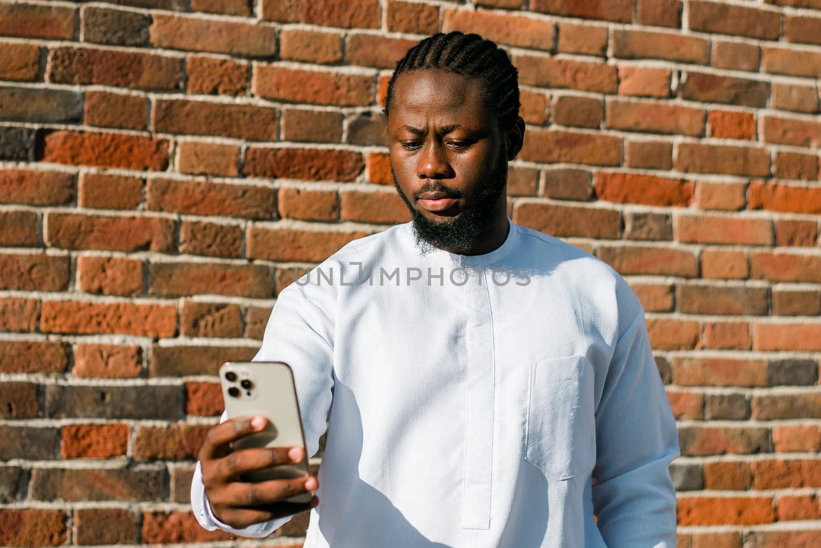 African american man checks cell phone in the street cafe in summer day. Millennial generation and gen z people. Social networks and dating app