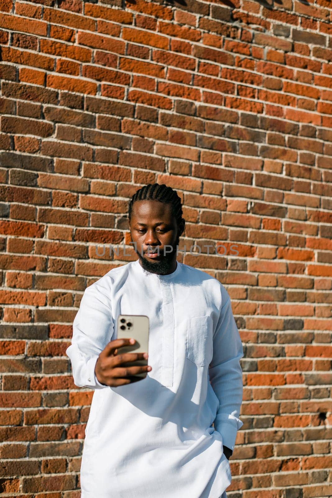 African american man checks cell phone in the street in summer day. Millennial generation and gen z people. Social networks and dating app concept by Satura86