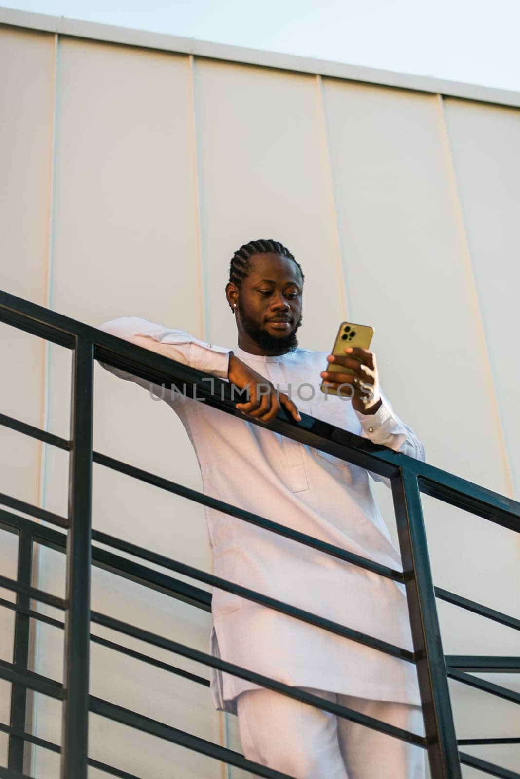 African american man checks cell phone in the street cafe in summer day. Millennial generation and gen z people. Social networks and dating app