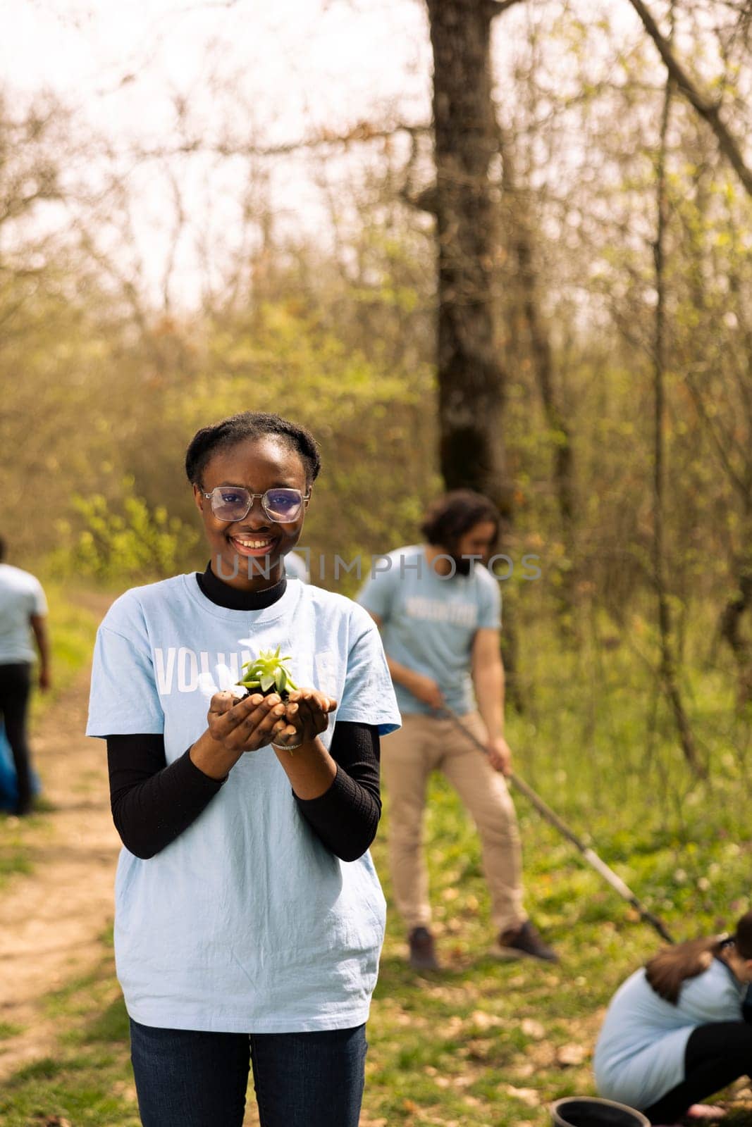 African american volunteer presents a vegetation seedling with organic soil by DCStudio