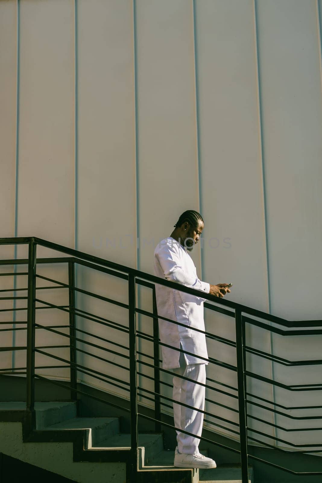 African american man checks cell phone in the street cafe in summer day. Millennial generation and gen z people. Social networks and dating app