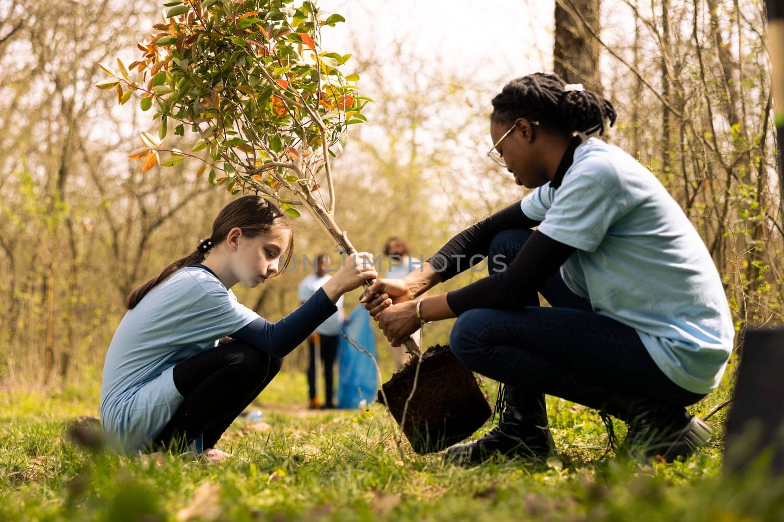 Small child and her colleague planting a tree in the forest by DCStudio