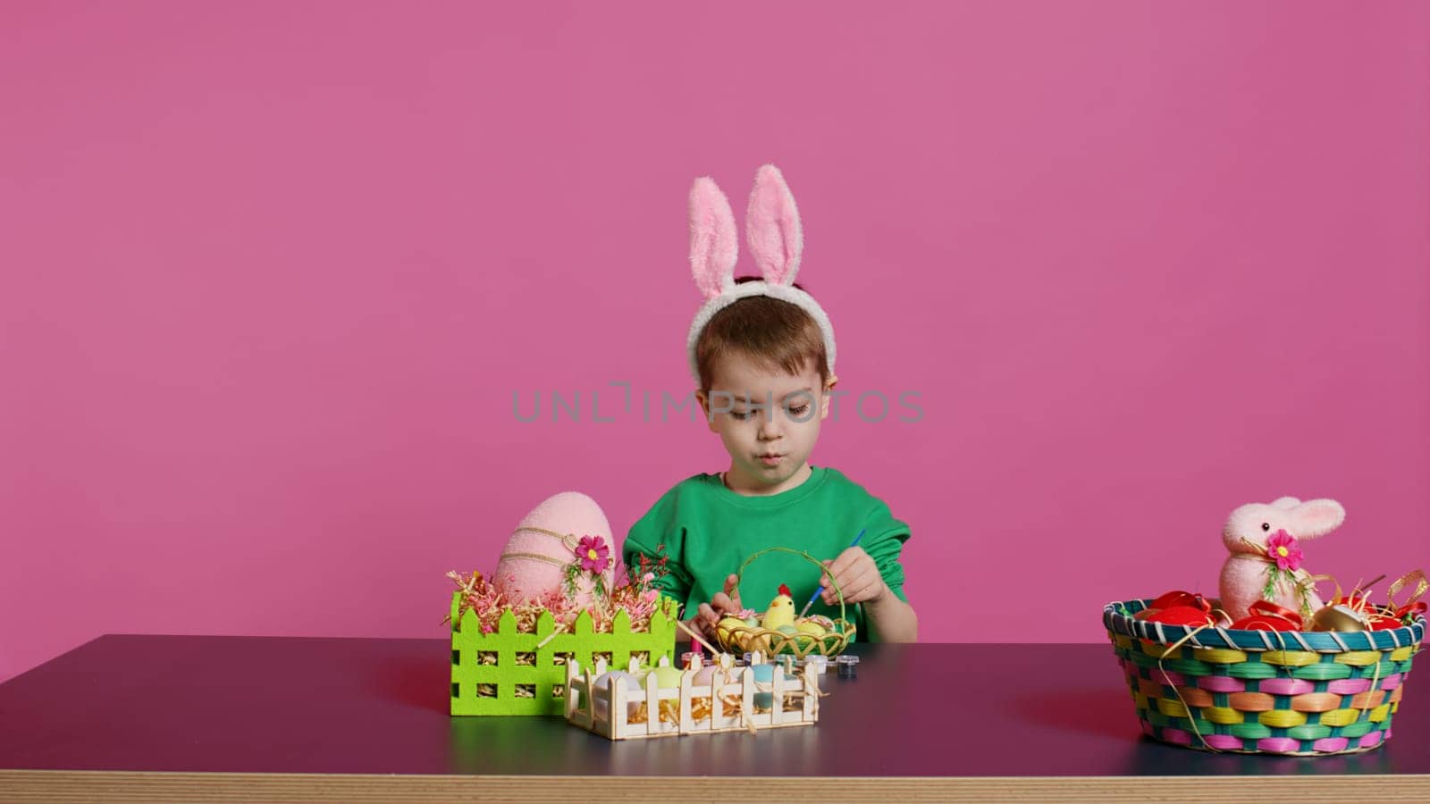 Happy small child arranging eggs and chick in a basket in preparation for easter by DCStudio