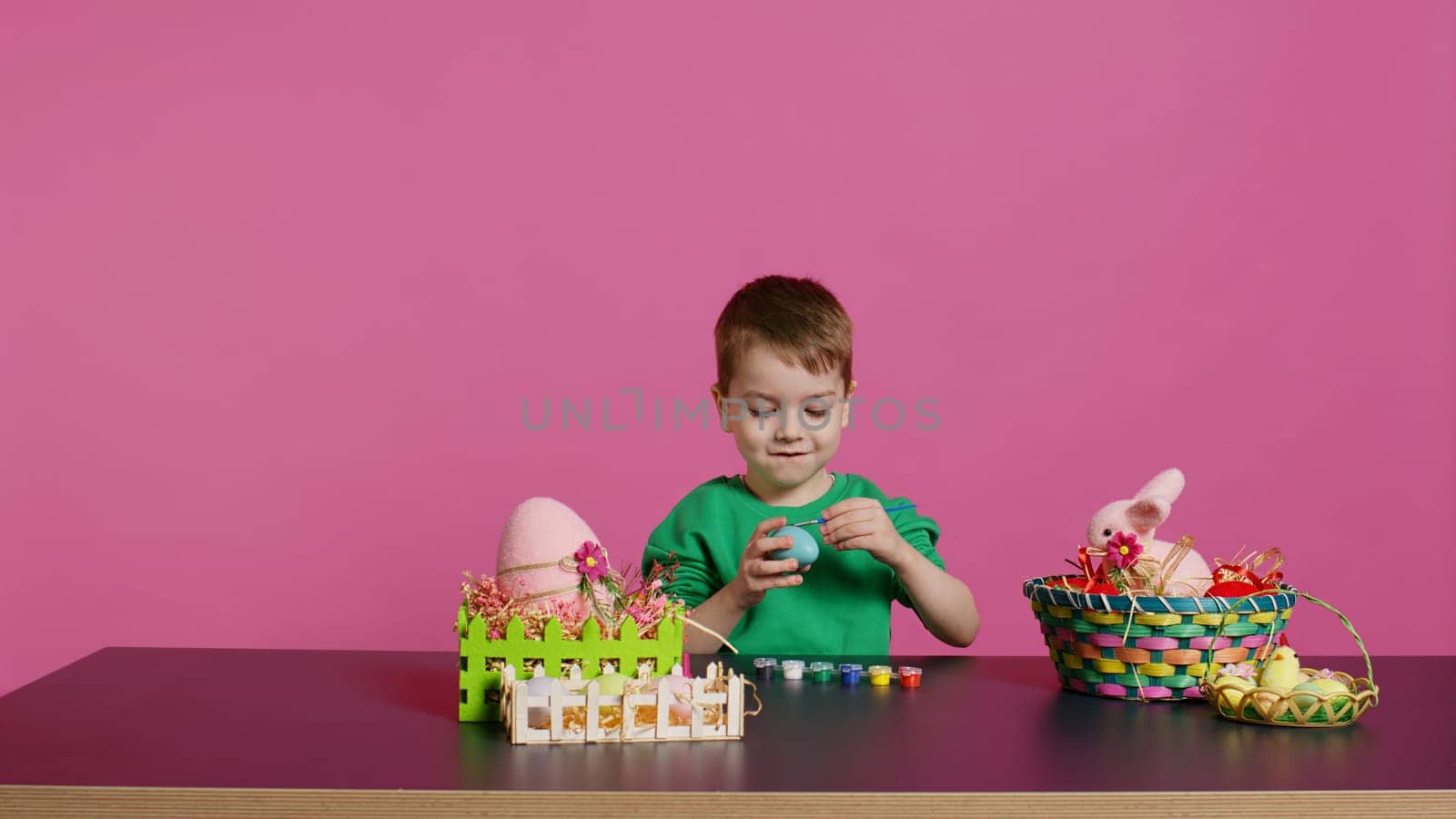 Little cheerful boy crafting handmade easter decorations by painting with watercolor and paintbrushes. Small young kid using art supplies coloring eggs for holiday, decorating activity. Camera B.