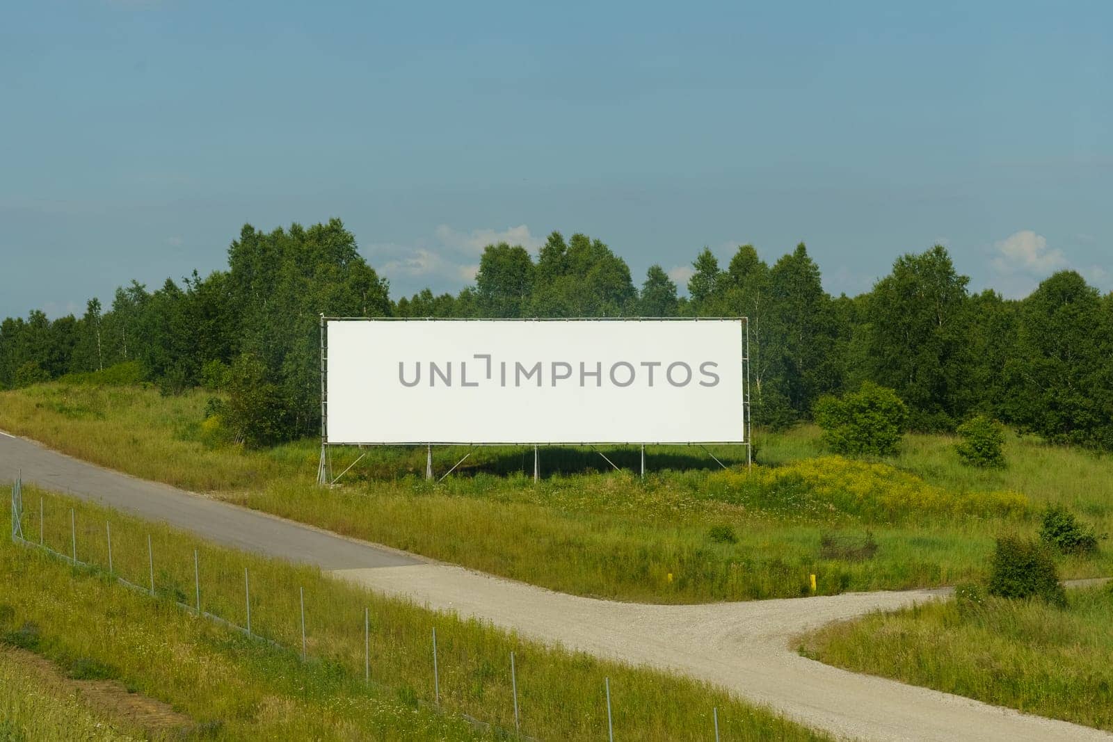 An empty billboard stands beside the road, awaiting a message or advertisement to capture passing drivers attention.