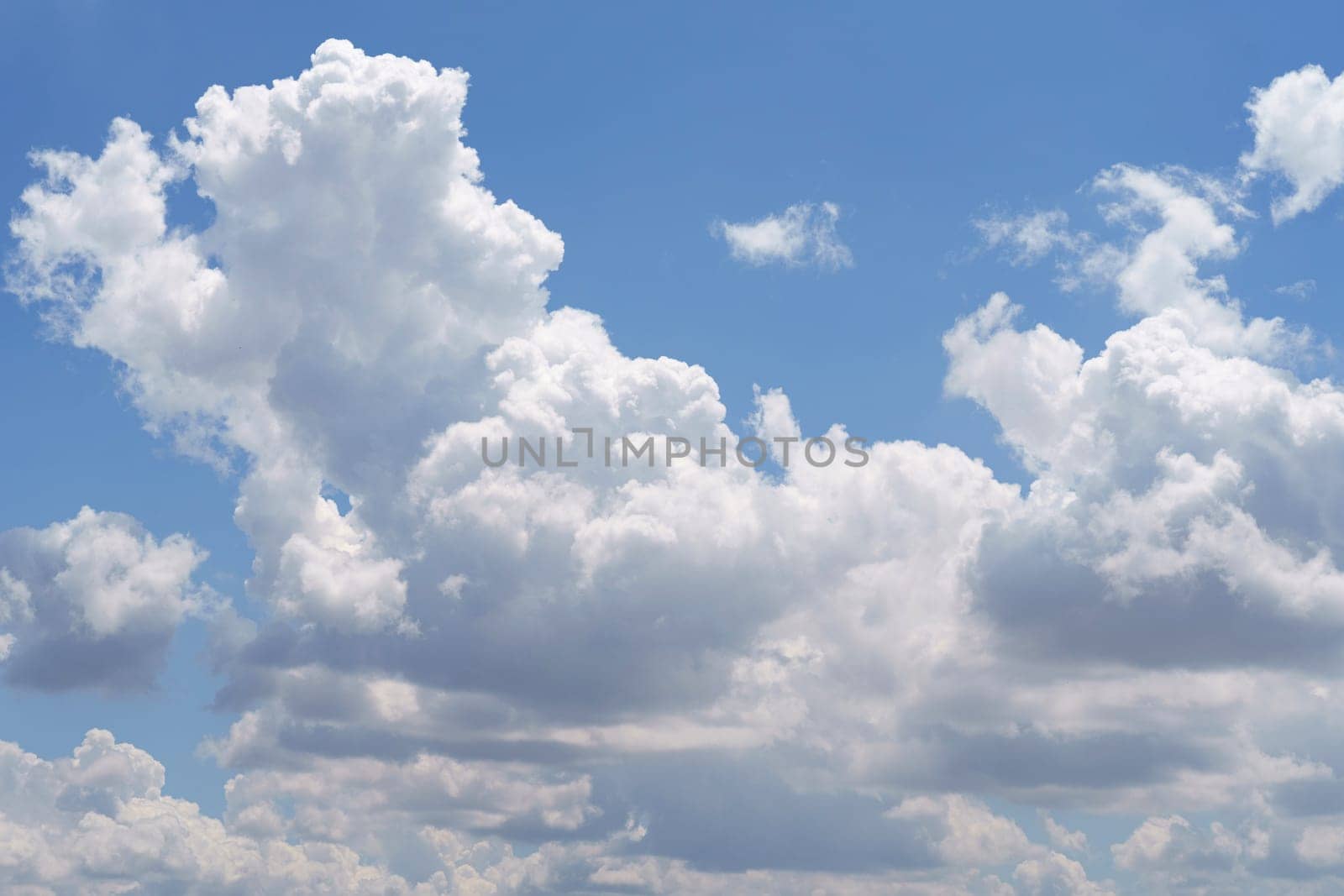 A plane soaring through a sky filled with fluffy white clouds on a sunny day.