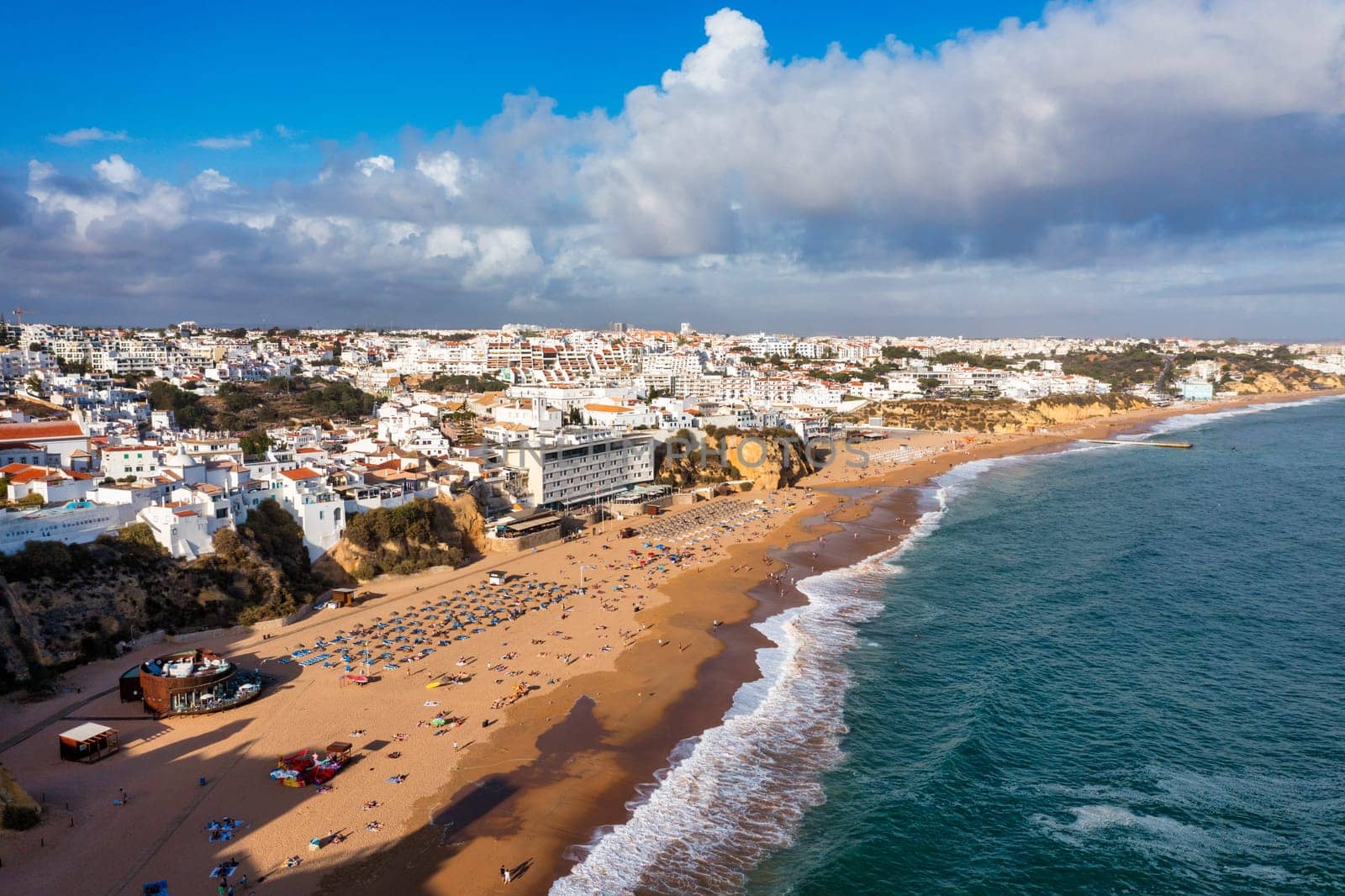Aerial view of seaside Albufeira with wide beach and white architecture, Algarve, Portugal. Wide sandy beach in city of Albufeira, Algarve, Portugal. Aerial view of Albufeira town, Algarve, Portugal.