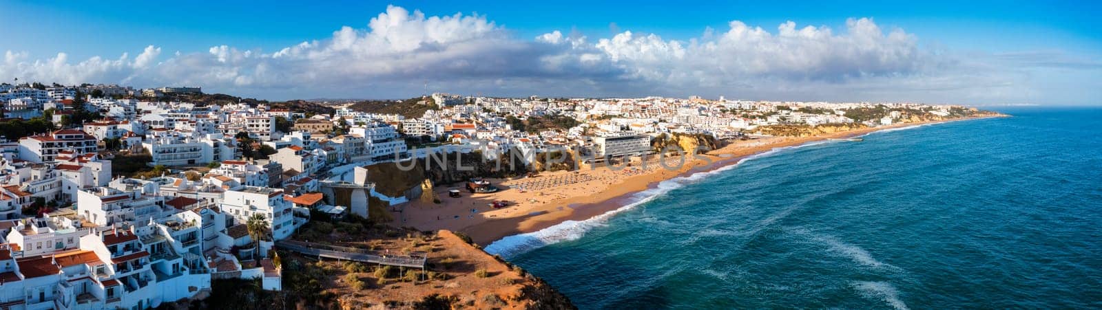 Aerial view of seaside Albufeira with wide beach and white architecture, Algarve, Portugal. Wide sandy beach in city of Albufeira, Algarve, Portugal. Aerial view of Albufeira town, Algarve, Portugal.