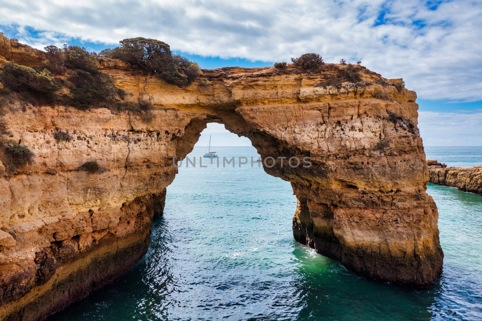 Natural arch above ocean, Arco de Albandeira, Algarve, Portugal. Stone arch at Praia de Albandeira, Lagoa, Algarve, Portugal. View of the natural arch Arco da Albandeira in the Algarve, Portugal.