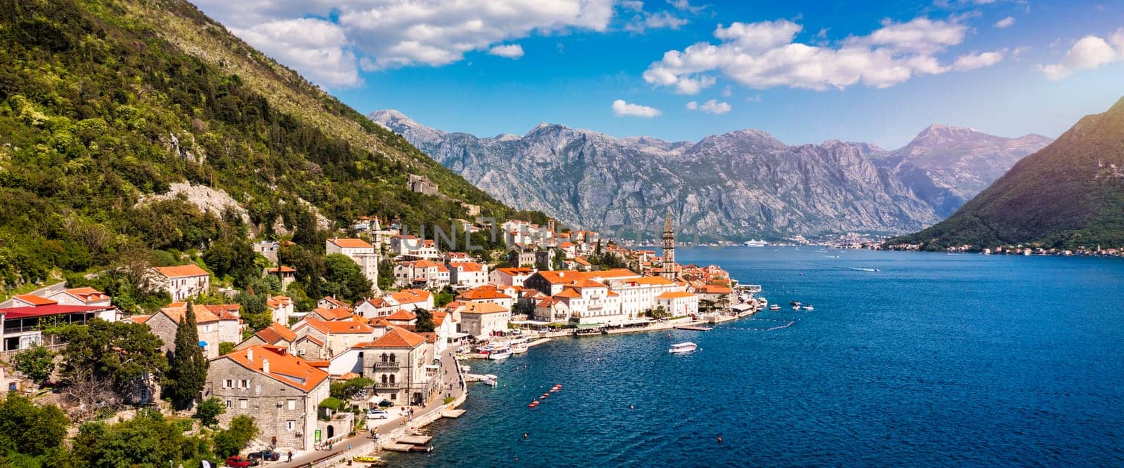 View of the historic town of Perast at famous Bay of Kotor on a beautiful sunny day with blue sky and clouds in summer, Montenegro. Historic city of Perast at Bay of Kotor in summer, Montenegro.