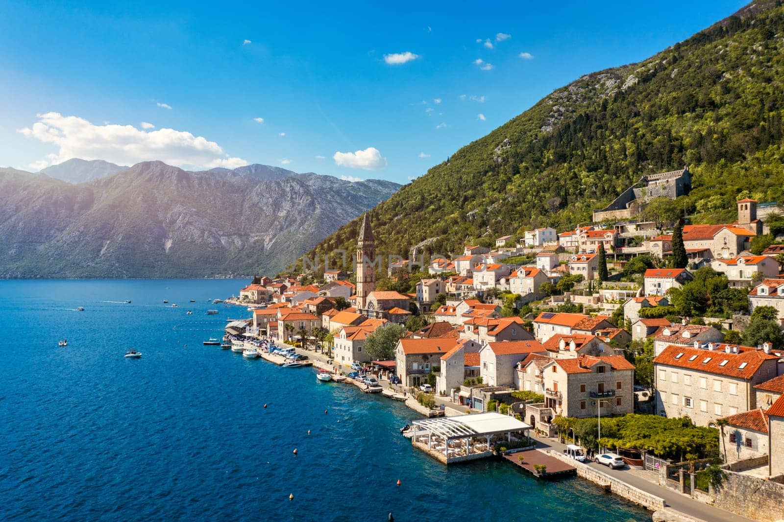 View of the historic town of Perast at famous Bay of Kotor on a beautiful sunny day with blue sky and clouds in summer, Montenegro. Historic city of Perast at Bay of Kotor in summer, Montenegro.