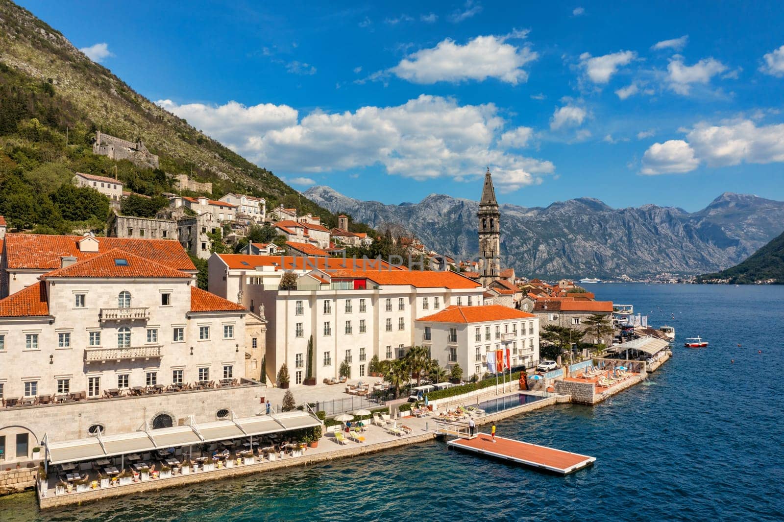 View of the historic town of Perast at famous Bay of Kotor on a beautiful sunny day with blue sky and clouds in summer, Montenegro. Historic city of Perast at Bay of Kotor in summer, Montenegro.