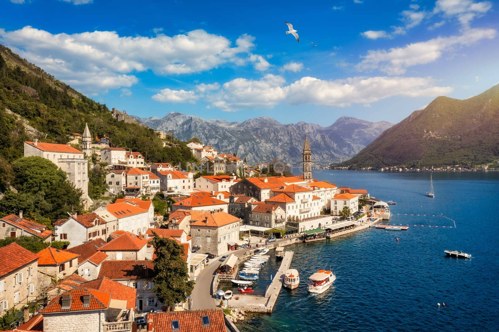 View of the historic town of Perast at famous Bay of Kotor on a beautiful sunny day with blue sky and clouds in summer, Montenegro. Historic city of Perast at Bay of Kotor in summer, Montenegro.